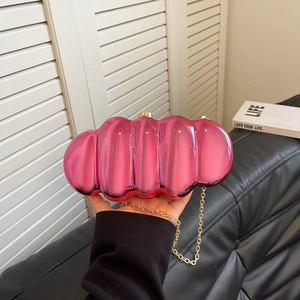 Pink marbled acrylic evening clutch bag with gold chain strap held by a fashion model