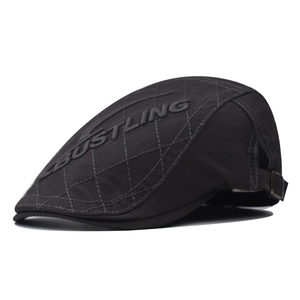 Detail view of black vintage flat cap with quilted texture and metal adjustment buckle