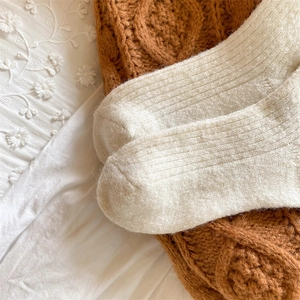 Close-up of white cable knit wool socks featuring delicate floral embroidery detail
