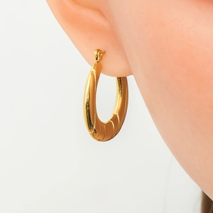 Macro view of polished 18K gold plated stainless steel hoop earring on model ear
