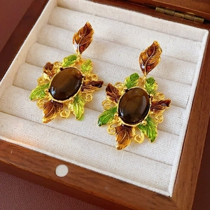 Gros plan de boucles d'oreilles vintage avec feuilles en émail et gemme marron en boîte