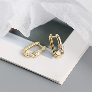 Macro detail of gold S925 silver U-shape buckle earrings with sparkling zircon inlay