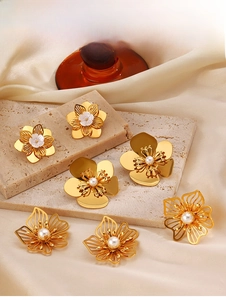 Detailed close-up of golden floral earrings with white pearls on a travertine stone stand