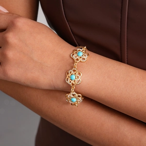 Close-up of gold flower bracelet with turquoise center stones and white rhinestones