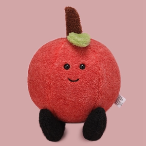 Cute plush red apple toy with green leaf and brown stem on soft pink background