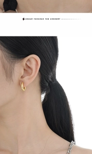 Close-up of golden S925 sterling silver hoop earrings with hammered texture on a model