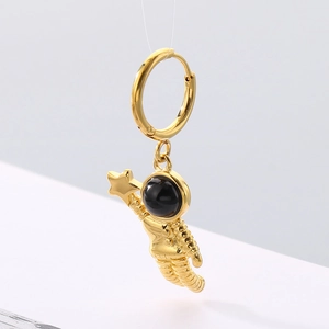 Detailed macro view of a gold astronaut earring with a black helmet and a tiny star charm