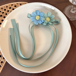 Detailed view of blue floral hair clip with long mint green ribbons on ceramic plate