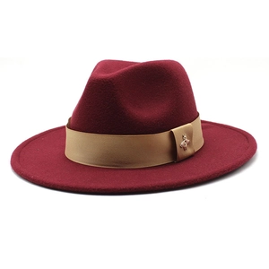 Detail of burgundy wool fedora featuring khaki ribbon and small gold bee metal emblem