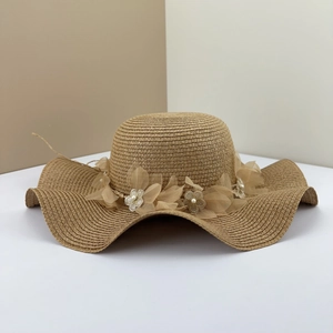 Détail du chapeau de paille à bords ondulés avec fleurs en tulle et perles blanches