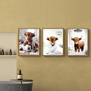Detailed view of three highland cow art prints in wooden frames on a bathroom wall