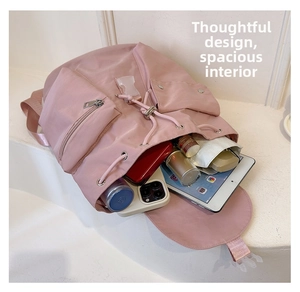 Pink nylon backpack with open interior showing tablet, bottle and pocket storage