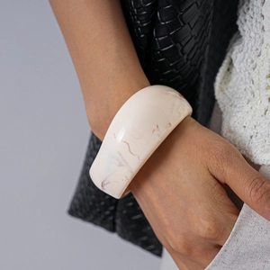 Detailed close-up of cream marble acrylic bangle on wrist with elegant minimalist styling