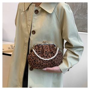 Close-up of leopard print shell bag with pearl handle and gold chain on beige coat