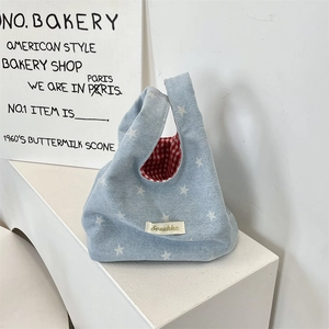 Detail view of denim star tote with red checkered lining and brand woven label