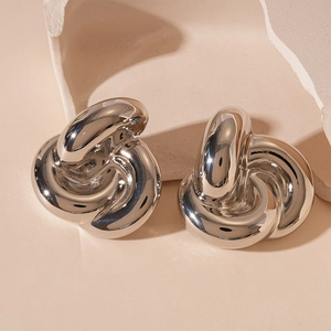 Detailed view of silver knotted earrings with a chunky metallic finish on artful props