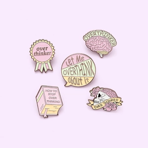 Pink Overthinker enamel pin set with skull and brain designs on light purple background