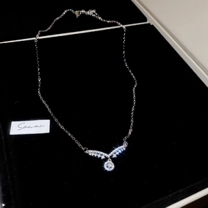 Vue macro d'un pendentif en V argenté orné de zircons et d'une grosse pierre ronde