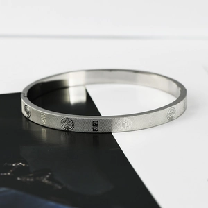 Detail of silver titanium steel bracelet featuring etched religious medal and grid pattern