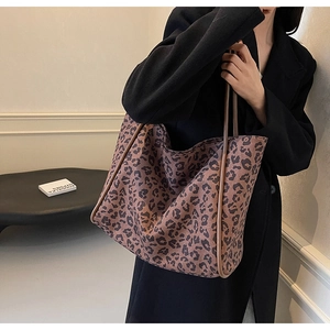 Close-up of a large leopard print tote bag styled with a long black wool coat