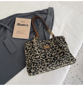 Detail of leopard print tote bag with brown leather straps and gold chain link accents