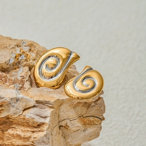 Orecchini a spirale bicolore in oro 18 carati e argento su superficie di pietra naturale