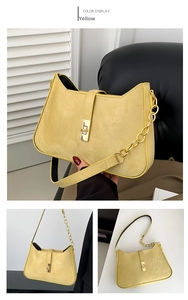 Detail of yellow suede shoulder bag featuring a gold metal lock and chain strap