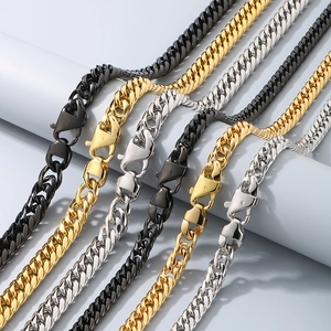 Classic Cuban link chains in gold, silver, and black finishes on a display cylinder