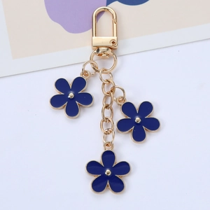 Detail of navy blue enamel flower keychain with gold-tone hooks and triple pendants