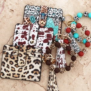 Three patterned leather card holders with silicone bead bracelets and tassels in macro view