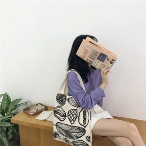 Detail of leaf print canvas tote bag carried by a model in a casual lifestyle setting