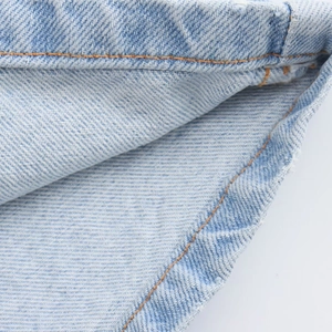 Close-up of blue denim fabric with high-quality twill texture and orange stitching