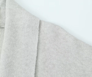 Close-up of light grey chunky knit cardigan fabric showing soft textured weave detail