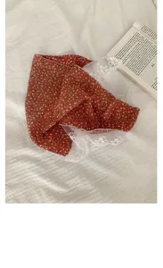 Macro detail of red floral headscarf with delicate white lace trim on waffle texture