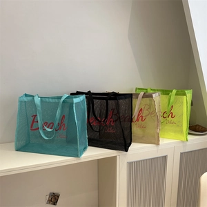 Mesh beach tote bags in four colors with Beach Vibes print on a white cabinet