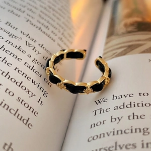 Gold plated open ring with black leather weave and zircon stars on vintage book