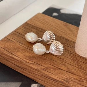 Elegant 925 silver shell earrings with pearls on a textured wooden background