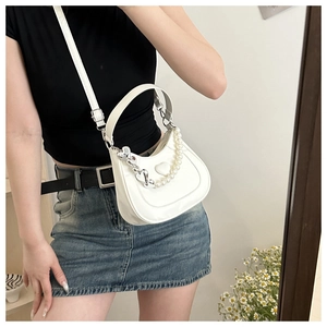 Detail of white half-moon bag with faux pearl chain and 3D heart-shaped texture