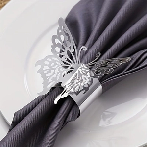 Close-up of a silver butterfly napkin ring with hollow design on a grey cloth