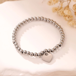 Fashionable silver beaded bracelet with heart pendant on a clean minimalist background