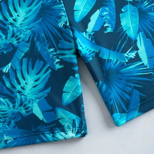 Détail de l'imprimé feuilles tropicales et coutures sur tissu bleu de maillot de bain