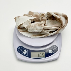 Detailed view of tie-dye chiffon hair scrunchie being weighed on a digital scale