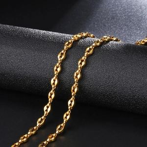 Macro shot of 4.5mm gold coffee bean links showing polished steel texture on black surface