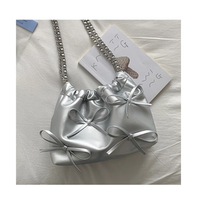 Close-up of silver PU leather pleated shoulder bag with 3D bows and chain strap