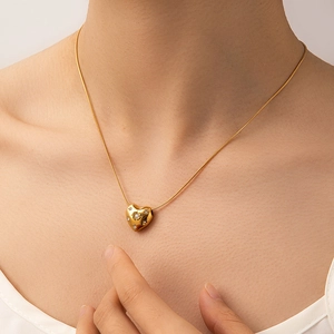 Dettaglio di una collana con ciondolo a cuore d'oro e piccoli diamanti su catena serpente
