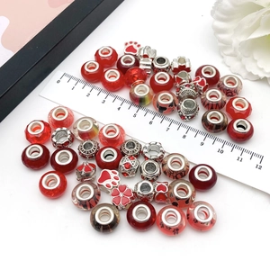 Macro detail of red DIY glass and enamel beads with ruler showing 1cm size for bracelets