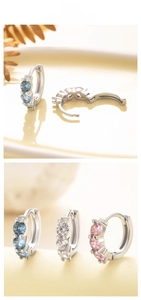 Detail view of silver huggie earrings set with light blue, white and pink cubic zirconia