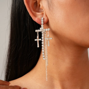 Detailed view of silver cross tassel earrings with sparkling rhinestones on model