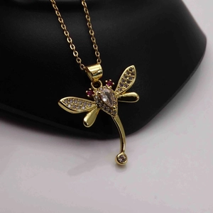 Detail of dragonfly pendant featuring gold plating, pink gems, and white zircons