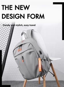 Detail showing the light grey backpack with orange zipper pulls and built-in USB charging port